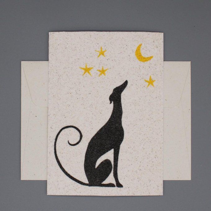 Carte de vœux en sable représentant un lévrier noir regardant un ciel étoilé avec lune jaune.