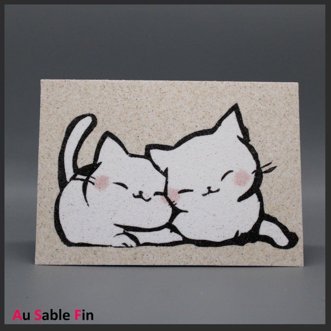 Carte de vœux en sable représentant deux chatons blancs blottis l’un contre l’autre, style kawaii.
