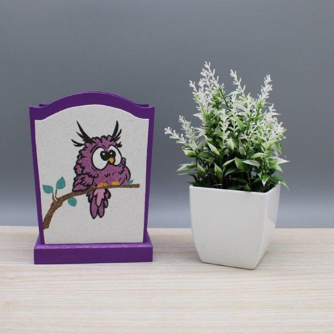  Pot à crayons hibou mauve à côté d’une plante décorative. 
