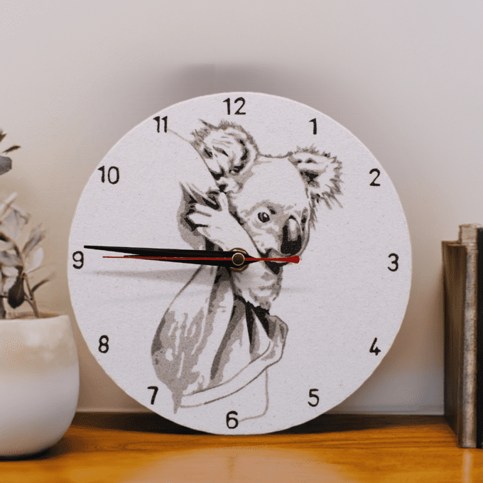 Horloge murale décorative – Duo de koalas en sable naturel sur support clair