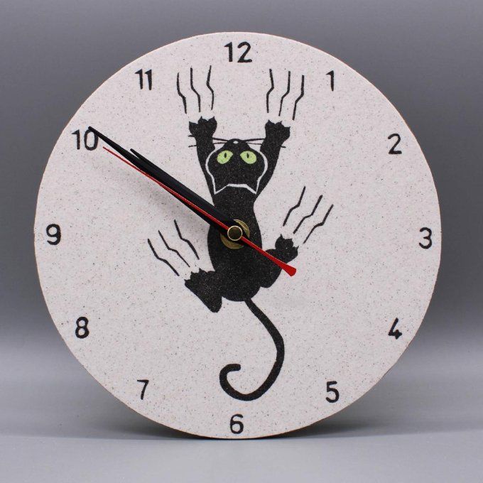 Horloge ronde « Cha glisse! » illustrant un chat accroché, en sable noir et jaune sur fond naturel