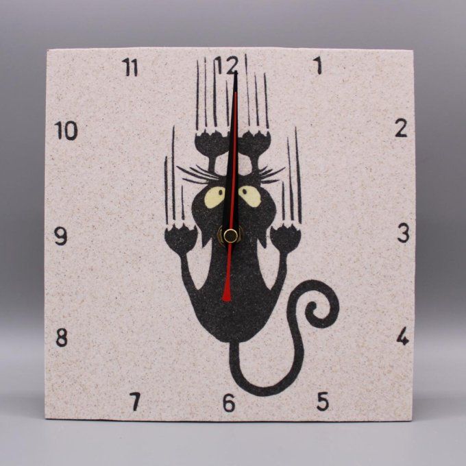 Horloge carrée « Oups cha glisse! » avec un chat accroché, sable noir et jaune sur fond naturel