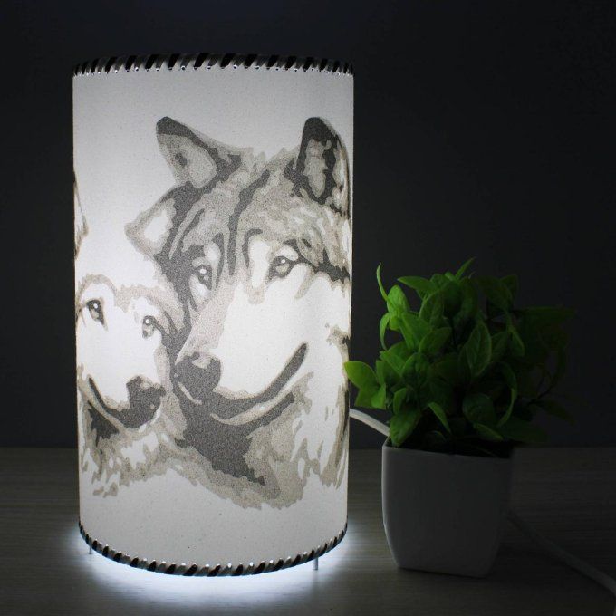 Lampe cylindre Tendresse sauvage – deux loups amoureux, réalisée en sable, tons gris, allumée