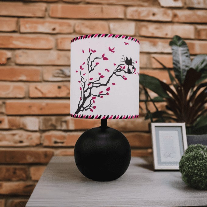 Lampe design chat noir sur branche fleurie – ambiance mur en briques