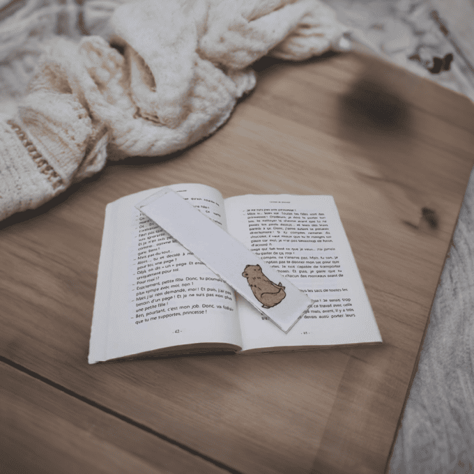 Marque-page original en sable sur livre – scène cocooning et bois clair