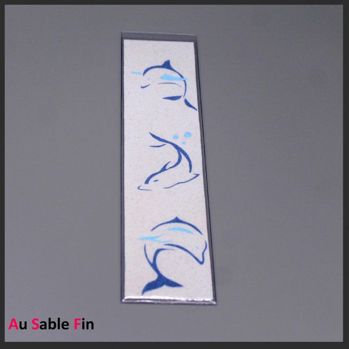 Marque-page avec trois dauphins bleus en sable sur fond blanc
