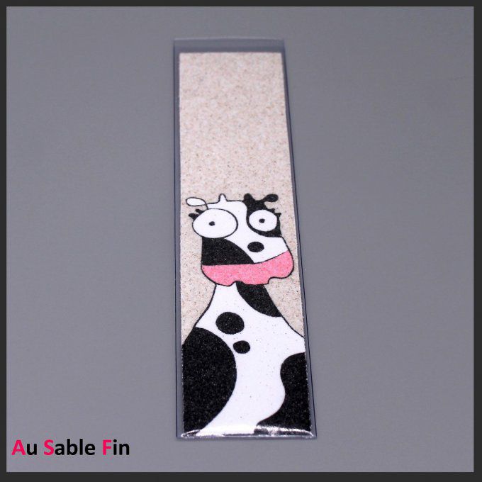 Marque-page vache noire et blanche avec museau rose en sable sur fond crème