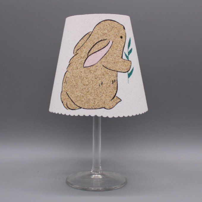 Photophore artisanal « Lapin » représentant un lapin tenant une brindille, en sable noir et naturel.