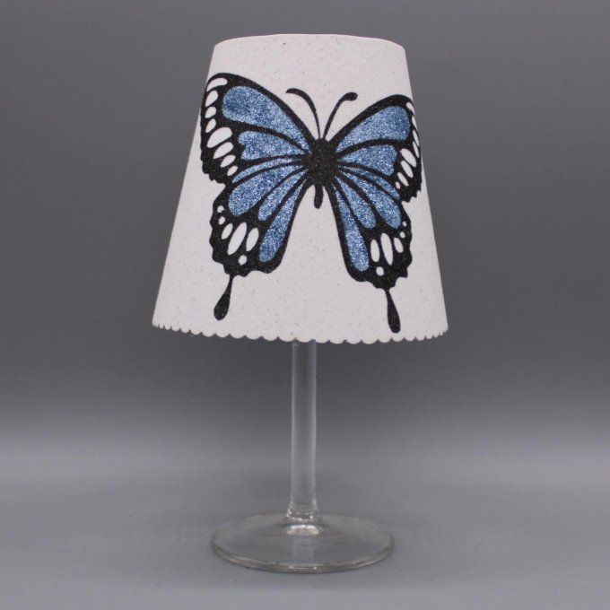 Photophore artisanal « Papillon ailes ouvertes » avec paillettes colorées bleues sur fond blanc.