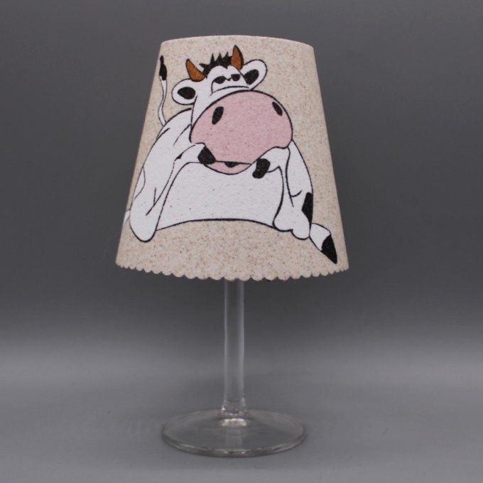 Photophore artisanal « Vache » en sable, posé sur un verre à vin.