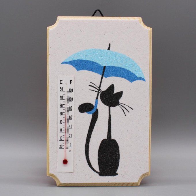 Thermomètre "Chat sous la pluie" représentant un chat noir sous parapluie bleu, en sable sur bois.