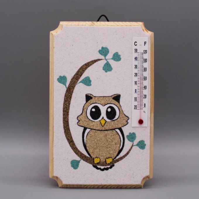 Thermomètre "Hibou" montrant un hibou sur une branche, en sable coloré sur fond blanc.