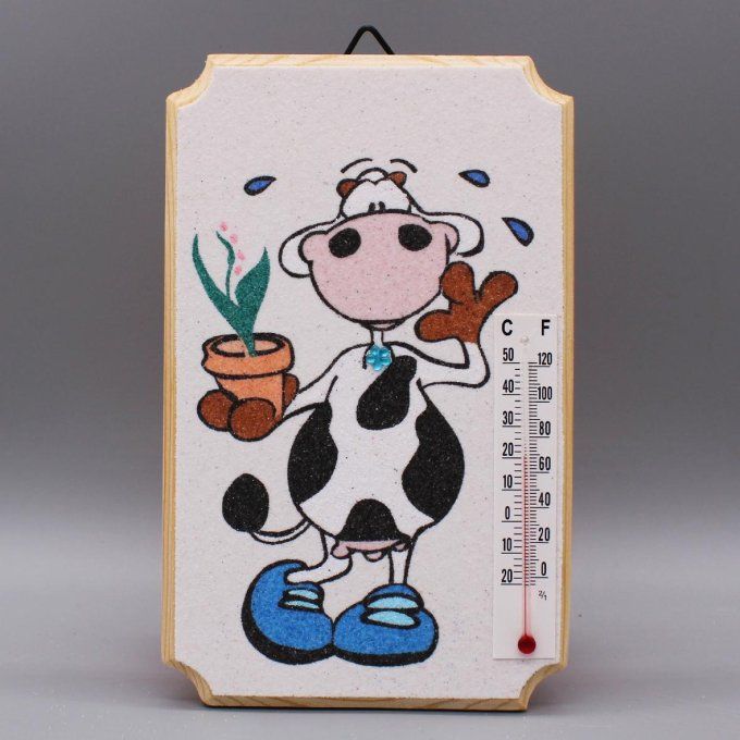 Thermomètre "Vache" montrant une vache tenant un pot de fleur, en sable sur fond blanc.